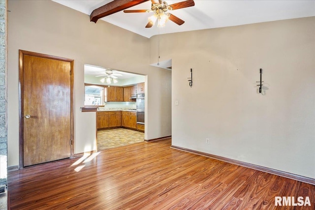 unfurnished living room with light hardwood / wood-style flooring, lofted ceiling with beams, and ceiling fan