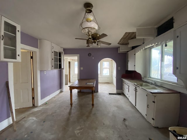 kitchen with hanging light fixtures, white cabinetry, sink, and ceiling fan