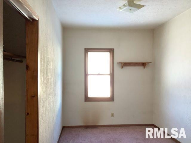 carpeted empty room featuring a textured ceiling