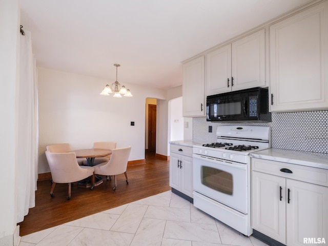 kitchen with white cabinetry, decorative light fixtures, white gas range, a notable chandelier, and backsplash