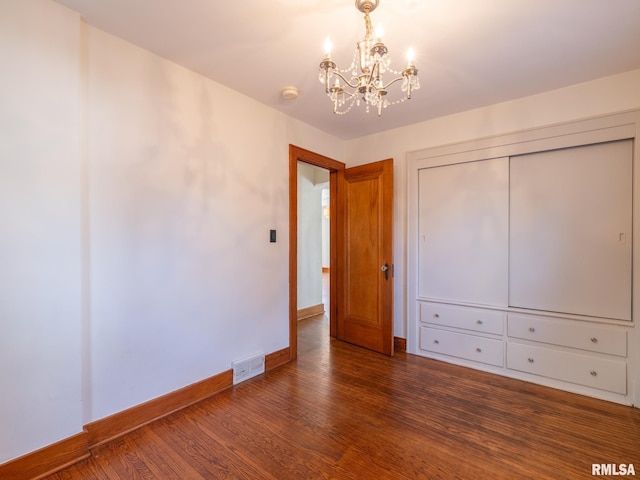 unfurnished bedroom with dark hardwood / wood-style floors, a notable chandelier, and a closet