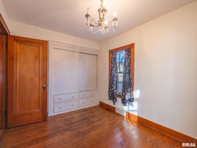 unfurnished bedroom featuring dark hardwood / wood-style flooring and a notable chandelier