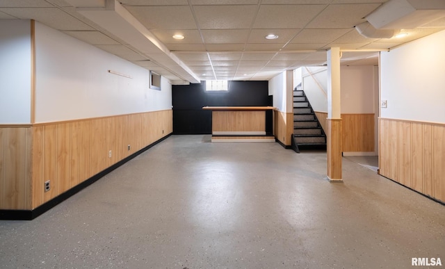 basement with wooden walls and a drop ceiling