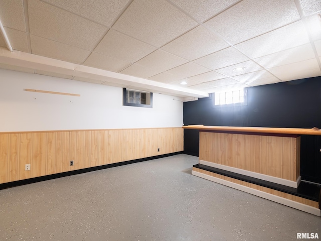 basement with wooden walls and a drop ceiling