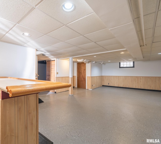 basement with wood walls and a drop ceiling