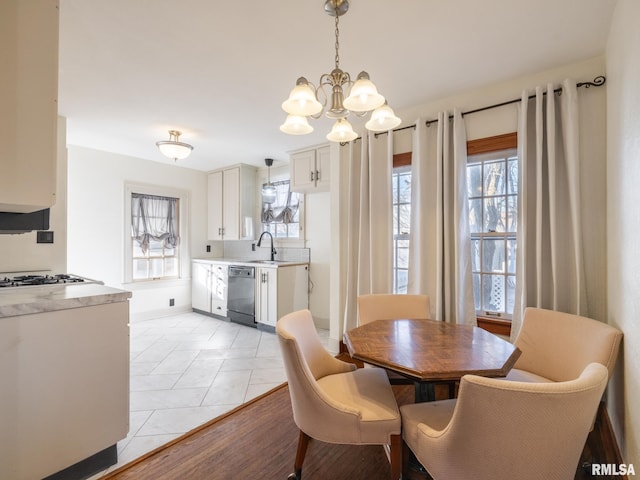 tiled dining area featuring sink, a notable chandelier, and a healthy amount of sunlight