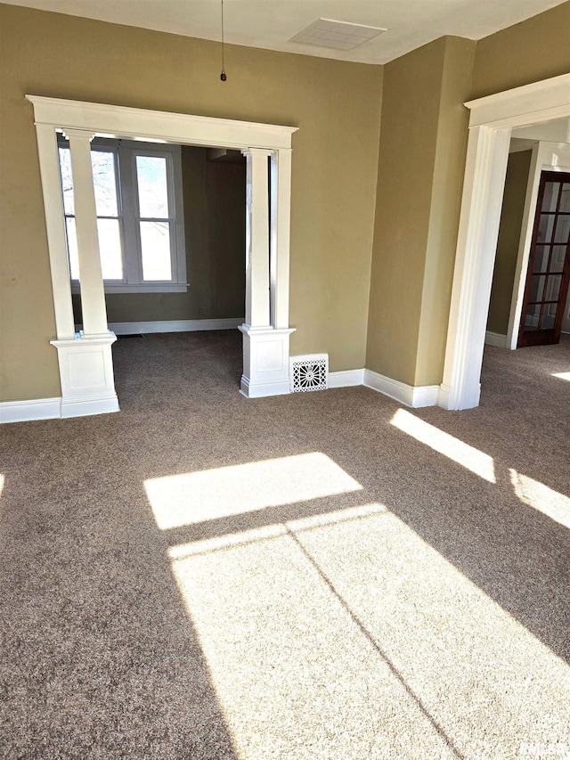 empty room featuring ornate columns and carpet flooring