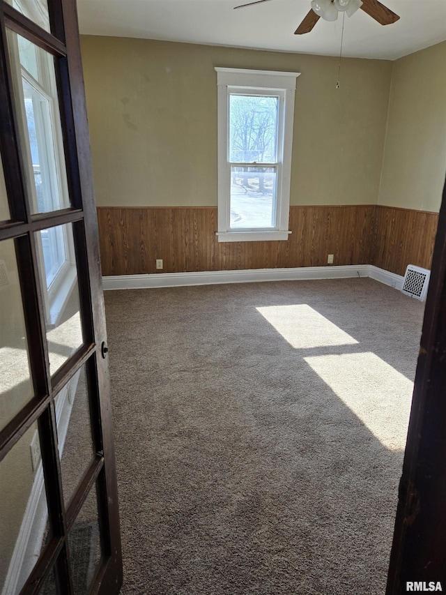 unfurnished room with carpet, ceiling fan, and wood walls