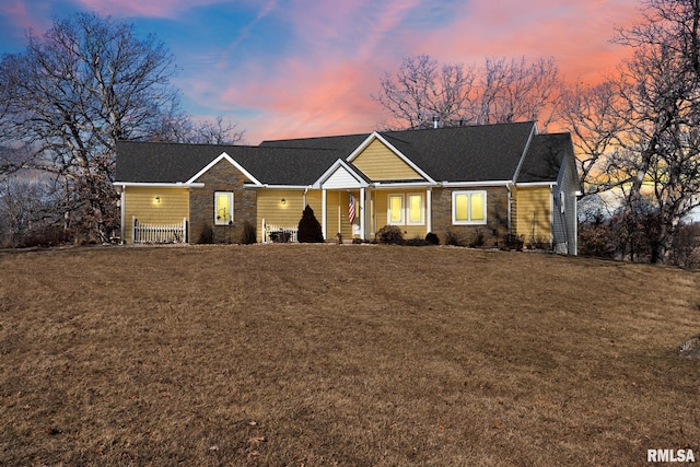 view of front of house with stone siding and a yard