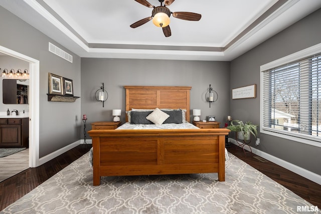 bedroom featuring baseboards, visible vents, a tray ceiling, and wood finished floors