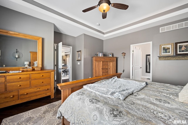 bedroom featuring dark wood-style flooring, a raised ceiling, visible vents, and a ceiling fan