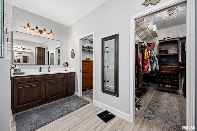 bathroom featuring baseboards, a walk in closet, vanity, and wood tiled floor