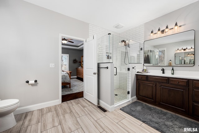 ensuite bathroom featuring connected bathroom, toilet, vanity, baseboards, and a stall shower