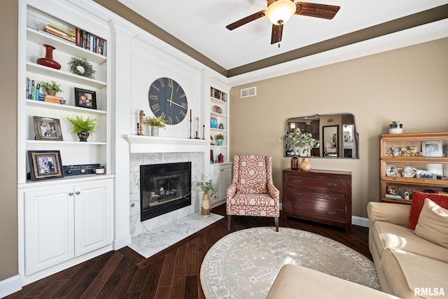 living room with built in shelves, dark wood finished floors, a fireplace, visible vents, and baseboards