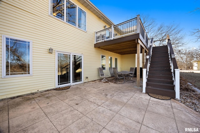 back of property with stairs, a patio, and outdoor dining space