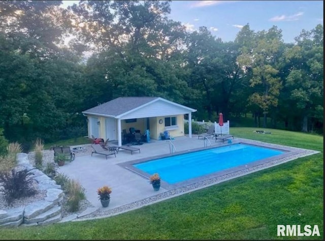 pool featuring an outbuilding, a yard, a patio area, and an exterior structure