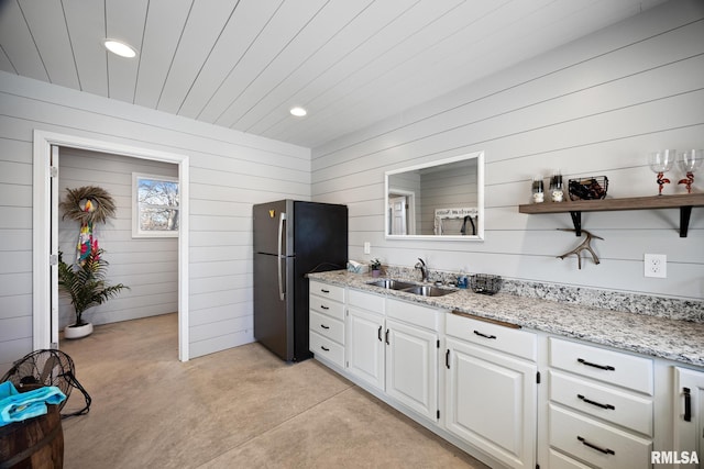 kitchen featuring light stone counters, a sink, white cabinets, freestanding refrigerator, and open shelves