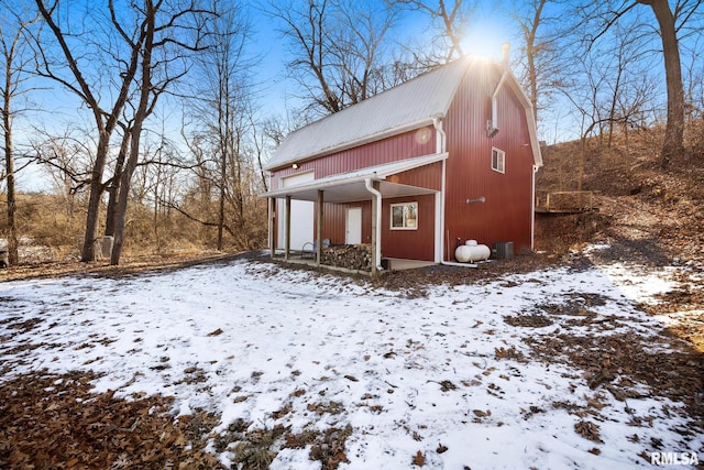 view of snowy exterior featuring a garage and a gambrel roof