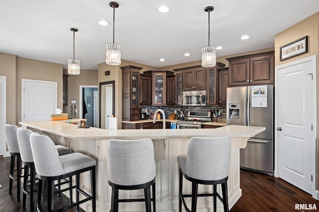 kitchen with dark brown cabinetry, a spacious island, glass insert cabinets, stainless steel appliances, and light countertops