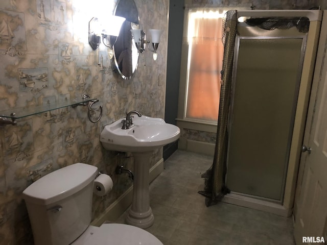 bathroom featuring a shower with shower door and toilet