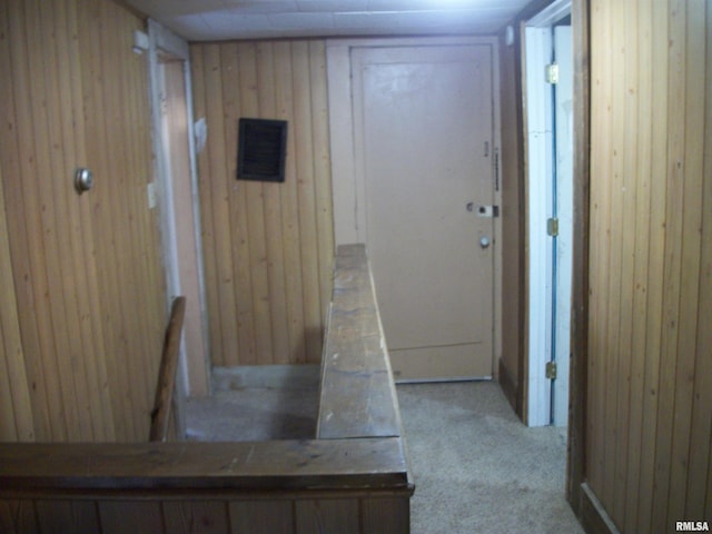 hall with light carpet and wood walls