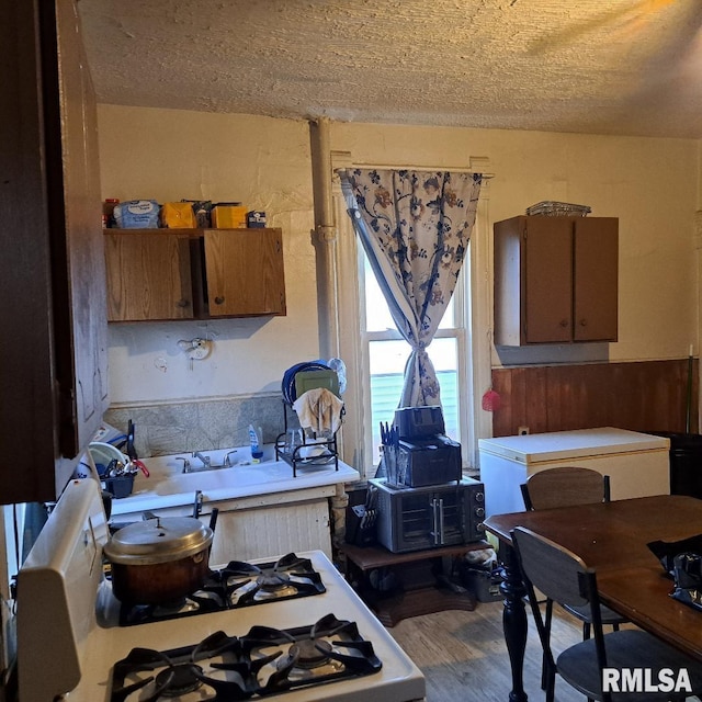 kitchen featuring hardwood / wood-style flooring, white range with gas stovetop, and a textured ceiling