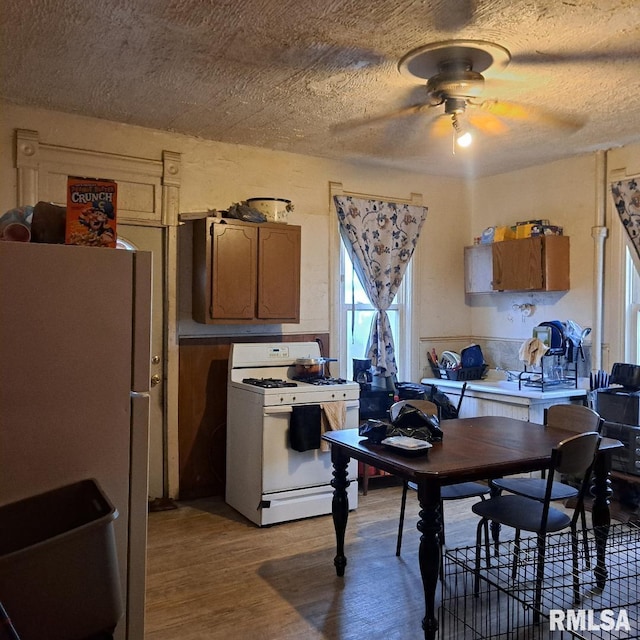 kitchen with ceiling fan, a textured ceiling, white appliances, and light hardwood / wood-style floors