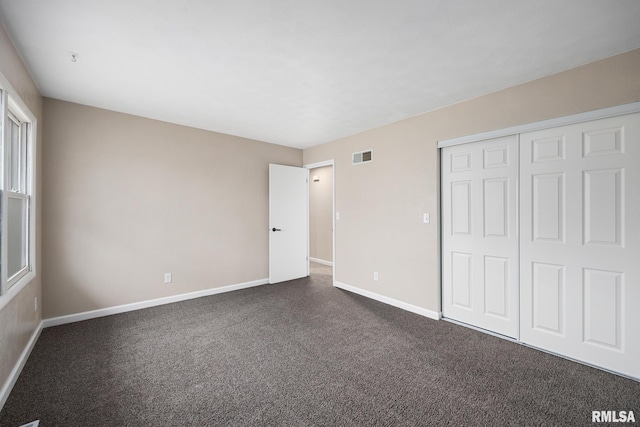 unfurnished bedroom featuring dark carpet and a closet