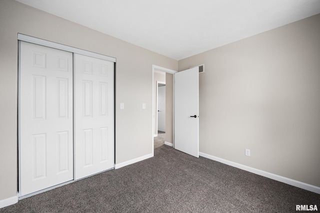 unfurnished bedroom with a closet and dark colored carpet