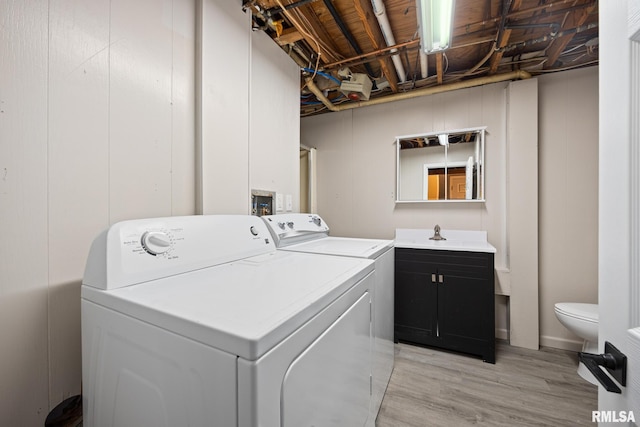 washroom featuring independent washer and dryer, sink, and light wood-type flooring