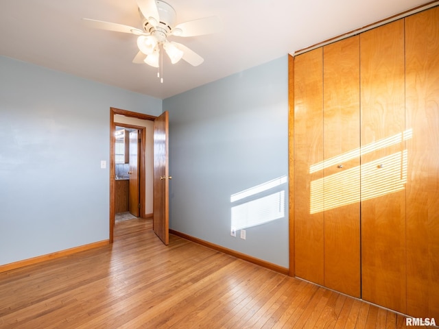 unfurnished bedroom featuring ceiling fan, a closet, and light wood-type flooring