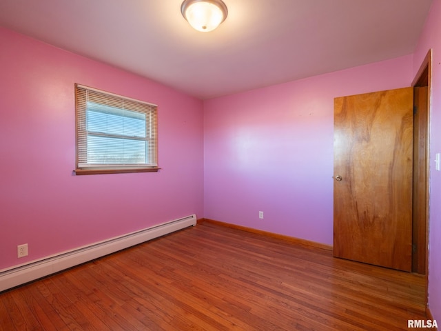 empty room with hardwood / wood-style flooring and a baseboard radiator