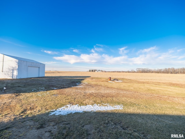 view of yard with a garage, an outdoor structure, and a rural view