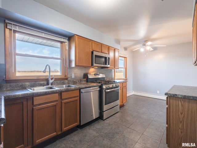 kitchen with appliances with stainless steel finishes, a wealth of natural light, sink, and backsplash