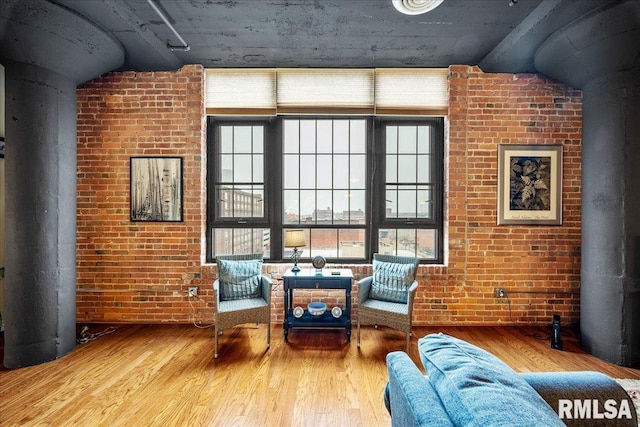 living area with hardwood / wood-style flooring, brick wall, and a wood stove