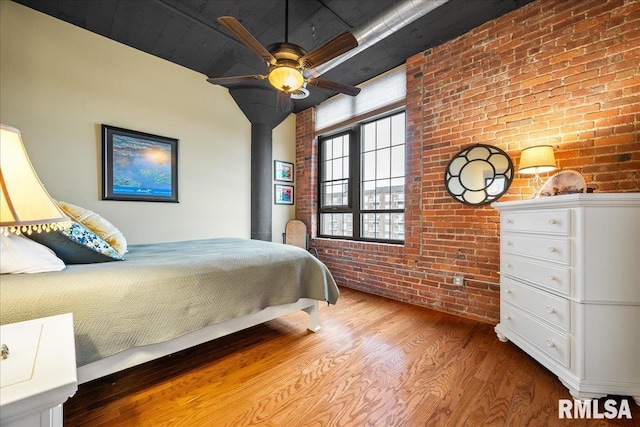 bedroom with brick wall and hardwood / wood-style floors