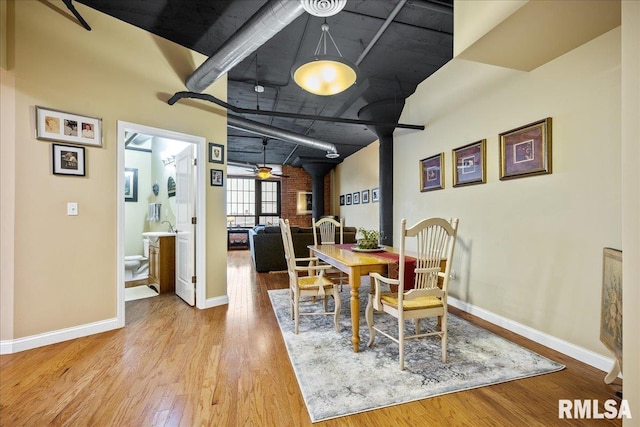 dining room with ceiling fan, light wood-type flooring, and a wood stove