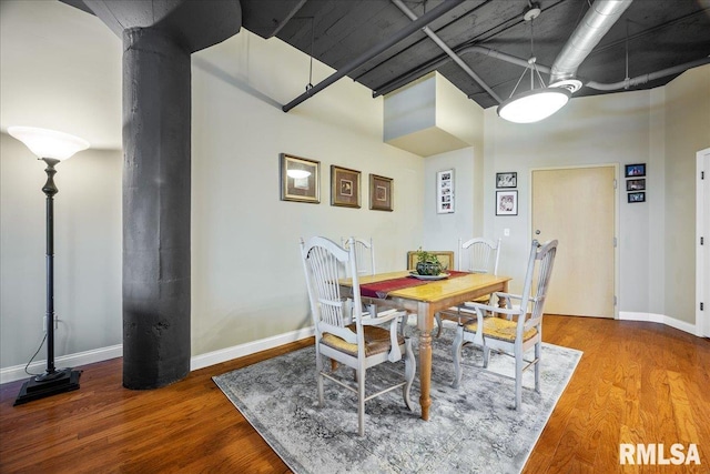 dining room with hardwood / wood-style flooring and a towering ceiling