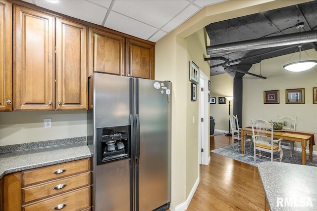 kitchen featuring stainless steel fridge, a drop ceiling, and light wood-type flooring