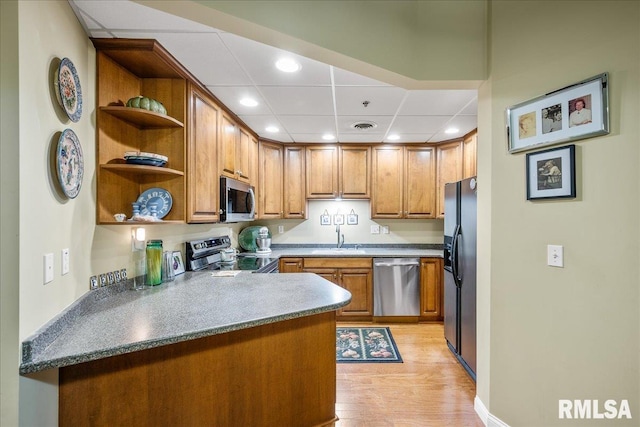 kitchen with appliances with stainless steel finishes, sink, light hardwood / wood-style floors, kitchen peninsula, and a drop ceiling