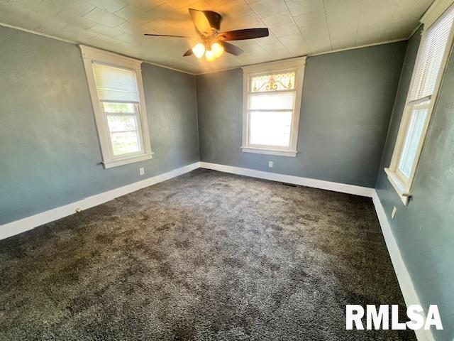 carpeted empty room with crown molding, plenty of natural light, and ceiling fan