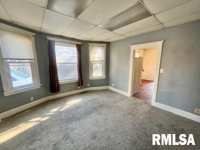 carpeted spare room featuring a drop ceiling