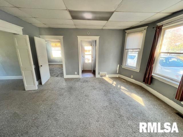 empty room with a paneled ceiling and carpet flooring