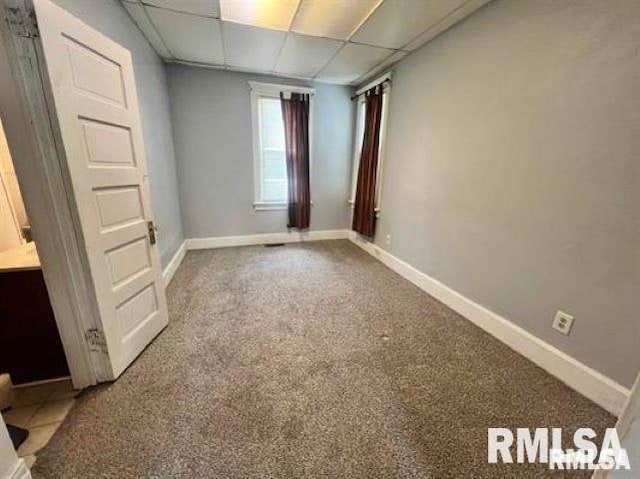 carpeted spare room featuring a paneled ceiling