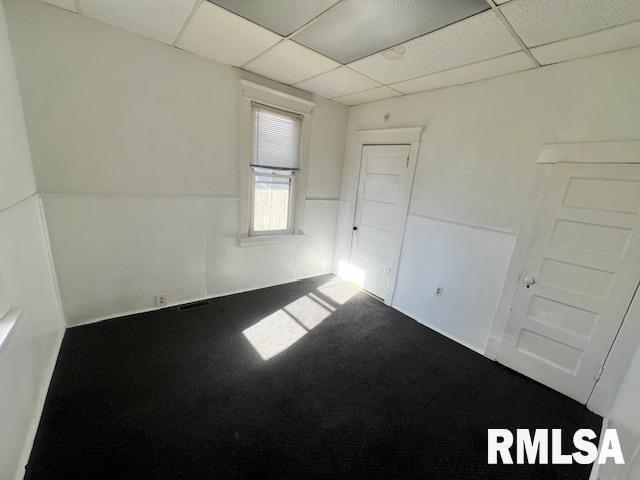 carpeted empty room with a paneled ceiling