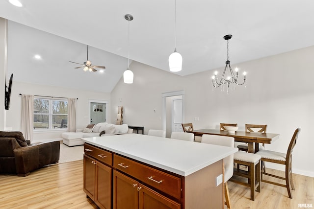 kitchen featuring a center island, high vaulted ceiling, light hardwood / wood-style flooring, pendant lighting, and ceiling fan with notable chandelier