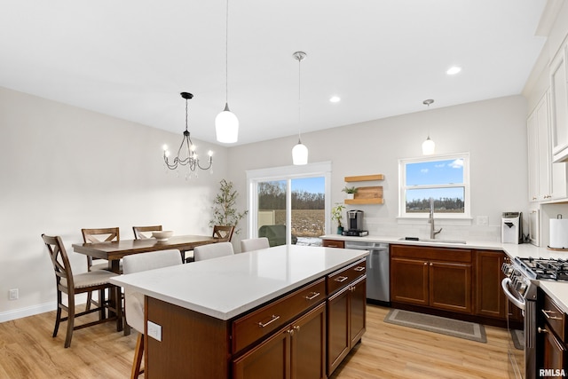 kitchen with sink, decorative light fixtures, a center island, light wood-type flooring, and stainless steel appliances