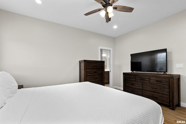 bedroom with connected bathroom, ceiling fan, and light hardwood / wood-style flooring