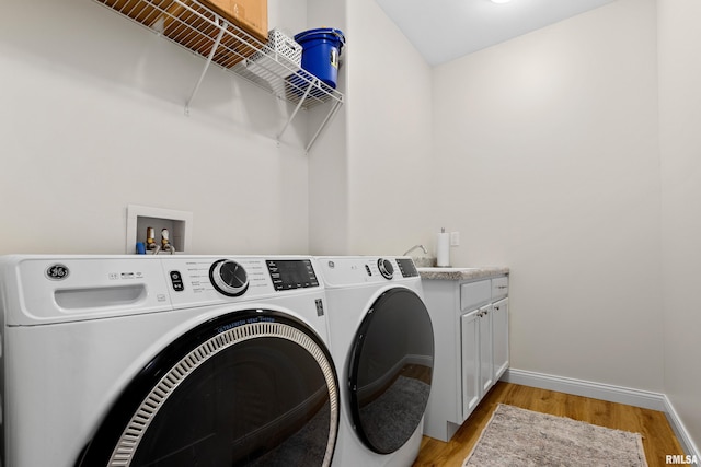 clothes washing area featuring cabinets, independent washer and dryer, and light wood-type flooring