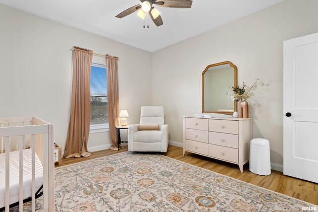 bedroom featuring ceiling fan, a nursery area, and light wood-type flooring